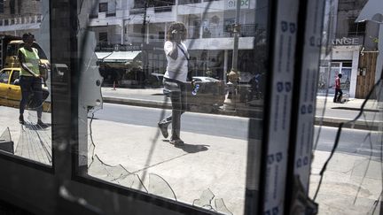 Le 5 juin 2023, une femme passe devant un magasin de station-service saccagé quelques jours plus tôt lors des manifestations à Dakar. (JOHN WESSELS / AFP)