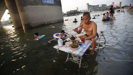 C'est ce qui s'appelle avoir les pieds dans l'eau. Un homme d&icirc;ne &agrave; Wuhan (Chine) alors que la temp&eacute;rature d&eacute;passe les 40&deg;C, le 28 juillet 2013. (MAXPPP)