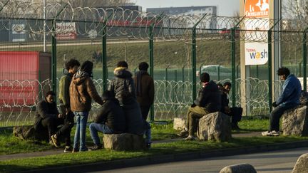 Des migrants attendent près d'un parking du terminal d'embarquement pour l'Angleterre, à Calais (Pas-de-Calais), le 12 janvier 2018. (PHILIPPE HUGUEN / AFP)