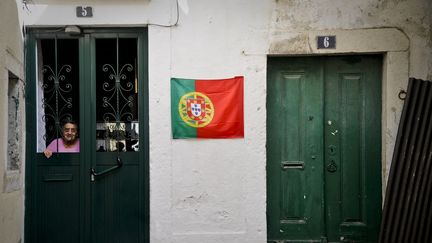 Une femme attend derrière la porte d'un immeuble dans le quartier d'Alfama, à Lisbonne, au Portugal. (PATRICIA DE MELO MOREIRA / AFP)