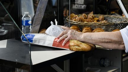 Un boulanger tend deux baguettes lors de la Fête du pain, à Paris, le 16 mai 2023. (MAGALI COHEN / HANS LUCAS / AFP)