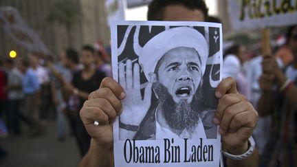 Un manifestant place Tahrir, au Caire&nbsp;(Egypte), brandit, le 7 juillet 2013, une affichette caricaturant Barack Obama en&nbsp;Oussama Ben Laden.&nbsp; (KHALED DESOUKI / AFP)