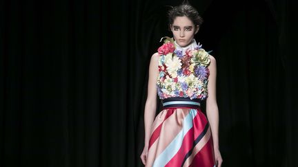 Après plusieurs saisons d'exploration du recyclage, Viktor &amp; Rolf a choisi de travailler avec un seul tissu : le satin duchesse, loin de l'esprit d'abondance que prône la haute couture. L'objectif : déclencher la créativité. Le satin duchesse a été travaillé pour créer des modèles graphiques audacieux : les rayures et les carreaux sont fabriqués à partir de patchwork méticuleux tissés. Ils sont juxtaposés avec des éléments organiques tels que des fleurs et des volants. Tous les vêtements sont coupés en biais.
 (Kamil Zihnioglu/AP/SIPA)