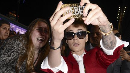 Le chanteur Justin Bieber se prend en photo aux c&ocirc;t&eacute;s de l'une de ses fans, le 18 d&eacute;cembre 2013, &agrave; Los Angeles (Etats-Unis).&nbsp; (DAN STEINBERG / AP / SIPA)