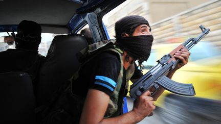 Des rebelles syriens guettent d'&eacute;ventuels snipers apr&egrave;s l'attaque d'un b&acirc;timent &agrave; Selehattin, pr&egrave;s d'Alep, le 23 juillet 2012. (BULENT KILIC / AFP)