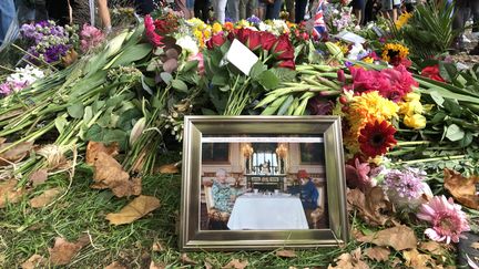 Une photo d'Elizabeth II, extraite d'un sketch diffusé à l'occasion du jubilé célébrant ses 70 ans de règne, a été déposée dans un parterre de fleurs, à Green Park, à Londres, le 11 septembre 2022.&nbsp; (MARIE-ADELAIDE SCIGACZ / FRANCEINFO)