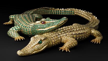 Collier Crocodiles. Cartier Paris, commande de 1975. Or, 1 023 diamants jaune fantaisie taille brillant pour un poids total de 60.02 carats, deux cabochons d’émeraude de forme navette (yeux). 1 060 émeraudes pour un poids total de 66.86 carats, deux cabochons de rubis (yeux)
	entièrement articulé, chaque crocodile peut se porter en broche. Afin de ne pas blesser le cou lorsqu’il est porté en collier, les pattes intérieures sont remplacées par des motifs qui simulent des pattes repliées. Commande spéciale de María Félix. Longueur 30 cm; longueur 27.3
 (V. Wulveryck, Collection Cartier © Cartier)