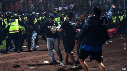 Des&nbsp;personnes portent un homme après un mouvement de foule dans un stade&nbsp;de Malang&nbsp;(Indonésie), le 1er octobre 2022.&nbsp; (AFP)