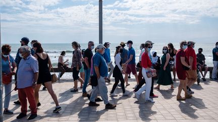 Des passants masqués profitent du soleil, samedi 29 mai 2021 à proximité de la plage de Saint-Gilles-Croix-de-Vie, en Vendée. (VALENTINO BELLONI / HANS LUCAS / AFP)