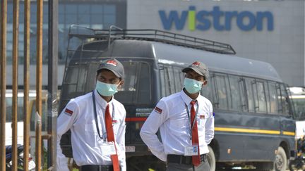 Des vigiles gardent l'entrée de l'usine Wistrom saccagée par des salariés à Bangalore (Inde), le 13 décembre 2020. (MANJUNATH KIRAN / AFP)