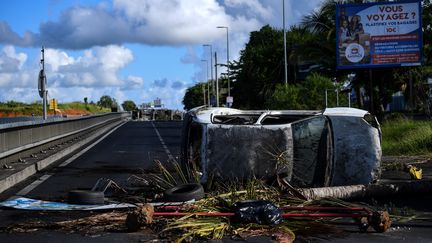 Un véhicule brûlé sur l'une des barricades érigées&nbsp;aux Abymes, près de Pointe-à-Pitre, en Guadeloupe, ce 22 novembre 2021. (CHRISTOPHE ARCHAMBAULT / AFP)