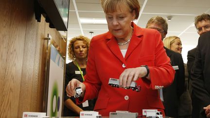 La chanceli&egrave;re allemande Angela Merkel joue avec des mod&egrave;les r&eacute;duits de camions lors d'une d&eacute;monstration interactive de logistiques au Future Logistics Living Lab &agrave; Sydney (Australie), le 17 novembre 2014. (JASON REED / REUTERS)