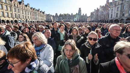 Des habitants d'Arras (Pas-de-Calais) se rassemblent sur la place des Héros, le 15 octobre 2023, pour rendre hommage à Dominique Bernard, professeur de lettres tué par un ancien élève, âgé de 20 ans et fiché S. L'homme né dans le Caucase avait auparavant enregistré un message de revendication et d'allégeance à Etat islamique (EI). (DENIS CHARLET / AFP)