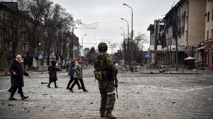 Des habitants passent devant un soldat russe dans le centre de Marioupol, le 12 avril 2022. (Illustration) (ALEXANDER NEMENOV / AFP)