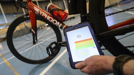 Un membre de&nbsp;l'Union cycliste internationale teste un dispositif pour repérer la présence d'un moteur sur les vélos, le 3 mai 2016. (FABRICE COFFRINI / AFP)