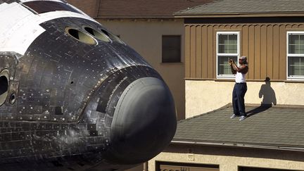 Un homme prend en photo la navette spatiale am&eacute;ricaine Endeavour lors de son transfert vers le California Science Center, &agrave; Los Angeles (Californie), le 13 octobre 2012. (RICK LOOMIS / REUTERS)