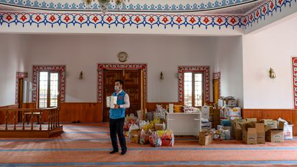 Abdulsamet Çakır, imam de la mosquée Dedeman, à Istanbul en Turquie, transporte des marchandises vers le vestibule transformée en épicerie gratuite pour les plus pauvres, le 21 avril 2020. (BULENT KILIC / AFP)