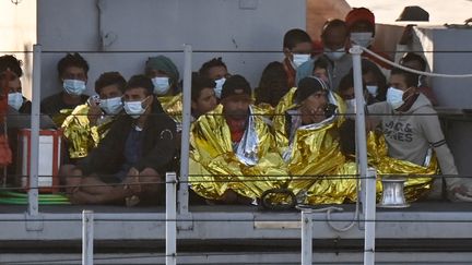 Des migrants pourvus de couverture de survie arrive sur un bâteau de la police douanière et financière italienne le 17 mai 2021 pour débarquer sur l'île de Lampedusa au Sud de l'Italie.

 (ALBERTO PIZZOLI / AFP)