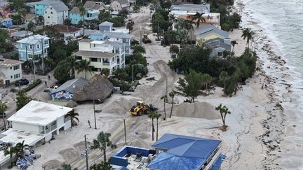 Des ouvriers débarrassent les routes du sable et des débris après le passage d'Hélène le 28 septembre 2024 à Treasure Island, en Floride. (JOE RAEDLE/GETTY IMAGES AMÉRIQUE DU NORD)