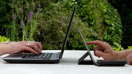 Deux personnes tapent sur un ordinateur et sur une tablette. (TRISTAN MARTIN#93398 / MOMENT MOBILE ED)