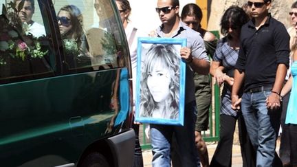 Un proche de la jeune Chloé, 15 ans, porte son portrait lors des obsèques de l'adolescente qui s'est suicidée (26/06/10) (AFP / Raymond Roig)