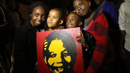 Pour la photo, des enfants se r&eacute;unissent autour d'une image repr&eacute;sentant Nelson&nbsp;Mandela, &agrave; Johannesbourg, le 6 d&eacute;cembre 2013. (ALEXANDER JOE / AFP)