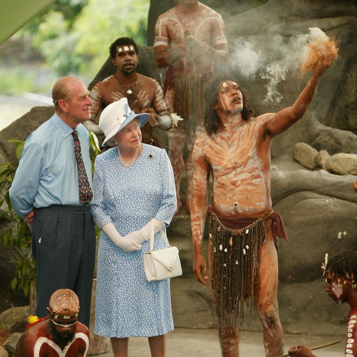 La reine Elizabeth II et le prince Philip observent des Aborigènes allumant un feu pour une cérémonie, à Cairns (Australie), le 1er janvier 2002. (TORSTEN BLACKWOOD / AFP)