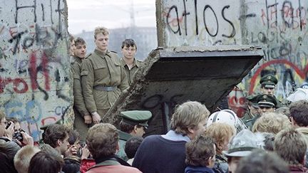 Incrédules, des gardes est-allemands assistent à la destruction d'un pan du mur de Berlin. (AFP / Gerard Malie)