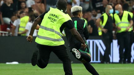 Un stadier poursuit un supporter entré sur le terrain, lors du match Nice-OM, le 22 août 2021. (VALERY HACHE / AFP)