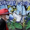 Une femme marche devant une fresque murale où est écrit "Atchoum ! Covid-19" dans les rues de Paris, le 20 avril 2020. (CHESNOT / GETTY IMAGES EUROPE)