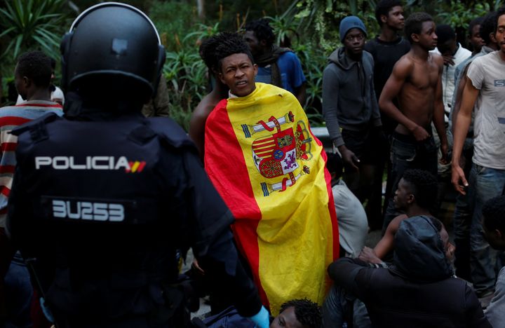 Un migrant&nbsp;revêt le drapeau espagnol après avoir franchi la clôture entre le Maroc et l'enclave espagnole de Ceuta, le 17 février 2017. (REUTERS)