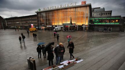 Des passants lisent les pancartes antisexistes laissées devant la gare de Cologne, le 11 janvier 2016, deux semaines après la vague d'agressions sexuelles du Nouvel An. (OLIVER BERG / DPA / AFP)