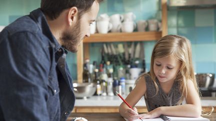 Un père surveille les devoirs de sa fille à la maison. Photo d'illustration. (SIGRID OLSSON / MAXPPP)