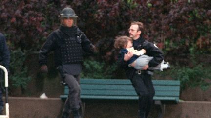 Evacuation d'un enfant de la maternelle Charcot à Neuilly,&nbsp;le 15 mai 1993.&nbsp;Le preneur d'otages Eric Schmitt, alias "Human Bomb",&nbsp;a été abattu de trois balles dans la tête. (PIERRE BOUSSEL / AFP)