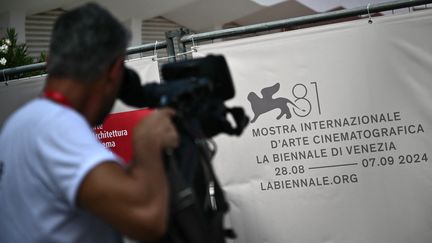 Un cameraman filme le logo de la 81e édition de la Mostra de Venise (Italie), le 27 août 2024. (MARCO BERTORELLO / AFP)