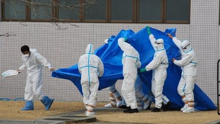 Ouvriers irradiés à la centrale nucléaire lors de leur déplacement au centre médical de Fukushima, le 25 mars 2011 (JIJI PRESS)