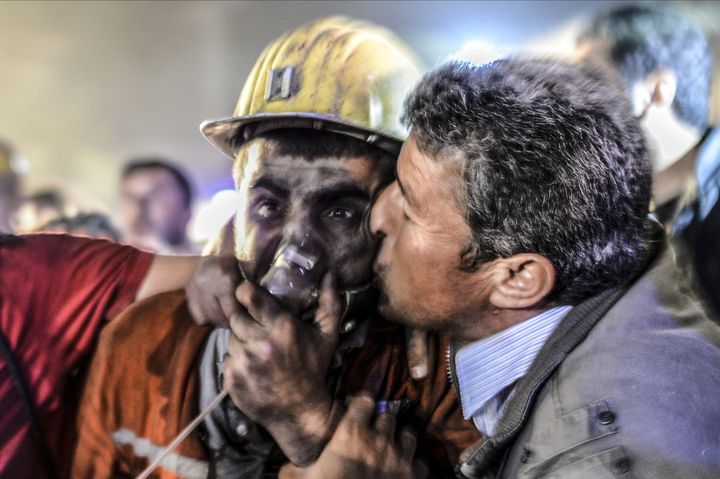 Un homme embrasse son fils, secouru des boyaux de la mine, &agrave; Soma, en Turquie, mardi 13 mai 2014. (BULENT KILIC / AFP)