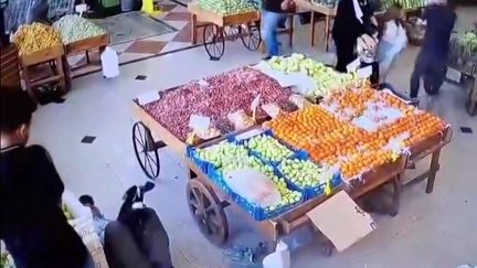 Cette capture d'écran d'une vidéo obtenue sur les réseaux sociaux semble montrer une explosion et un homme tombant au sol (à gauche) dans un marché couvert de légumes à Beyrouth. Des centaines de bipeurs utilisés par des membres du Hezbollah ont explosé à travers le Liban, le 17 septembre 2024. (- / ANONYMOUS)