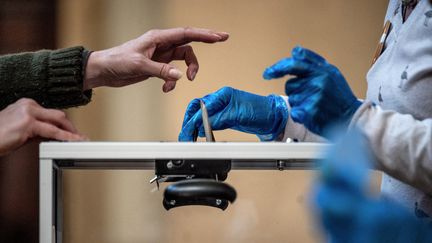 En pleine épidémie de coronavirus, une électrice dépose son bulletin dans une urne lors des élections municipales à Lyon (JEFF PACHOUD / AFP)