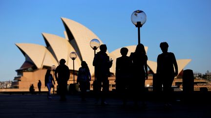 Des personnes marchent sur un quai à proximité de l'opéra de Sydey (Australie), le 2 novembre 2016. (STEVEN SAPHORE / REUTERS)