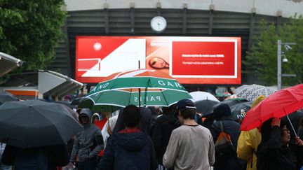 Des spectateurs patientent sous la pluie, mercredi 5 juin 2019 à Roland-Garros. (KAZUKI WAKASUGI / YOMIURI / AFP)