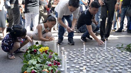 Des gens allument des bougies à Aubervilliers (Seine-Saint-Denis), le 14 août 2016, pour rendre hommage à Zhang Chaolin, un cuisinier Chinois assassiné dans la commune.&nbsp; (ALAIN JOCARD / AFP)