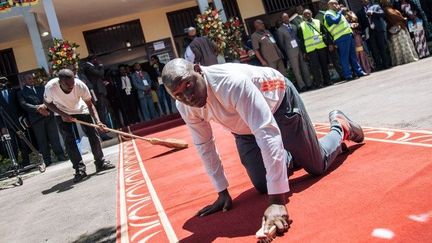 Des ouvriers préparent le tapis rouge qui doit accueillir un électeur pas comme les autres au bureau de vote. En effet, le candidat et président sortant Paul Biya se voit dérouler un tapis rouge pour aller voter avec son épouse dans le quartier de Bastos à Yaoundé. (ALEXIS HUGUET / AFP)