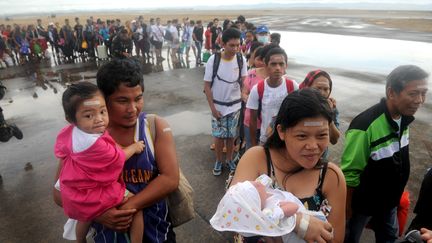 Des sinistr&eacute;s tentent de monter dans un avion C-130 sur l'a&eacute;roport de Tacloban (Philippines) le 13 novembre 2013. (NOEL CELIS / AFP)