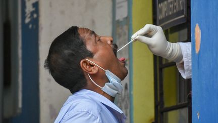 Un homme reçoit un écouvillon dans la bouche lors d'un test salivaire à Calcutta (Inde), le 22 octobre 2021. (DEBARCHAN CHATTERJEE / NURPHOTO)