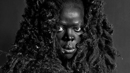 "La photographie qui donne le titre à la série ‘Somnyama Ngonyama’ est celle d’une Muholi au teint d’un noir d’ébène, avec une magnifique crinière tout aussi noire. L’image me désarçonne un peu, une lionne n’a pas de crinière, si ? Une recherche m’apprend que c’est rarement le cas. Or nous en voyons une dans cette série. Il me suffit toutefois de réfléchir pour comprendre que la crinière est un attribut clé pour un lion, alors comment aurait-elle pu représenter une lionne si elle ne l’avait pourvue d’une crinière, sans laquelle elle nous aurait apparue faible. Et la faiblesse, ce n’est pas Muholi. Cette photographie audacieuse est une proclamation sans concession du pouvoir de la négritude, de même qu’on ne peut prononcer le nom Somnyama Ngonyama sans se prosterner et lever les bras, comme on le ferait devant le membre d’une famille royale." Jackie Mondi, écrivaine, poétesse et professeure.&nbsp; &nbsp; (ZANELE MUHOLI, COURTESY OF STEVENSON GALLERY, CAPE TOWN/JOHANNESBURG, AND YANCEY RICHARDSON GALLERY, NEW YORK)