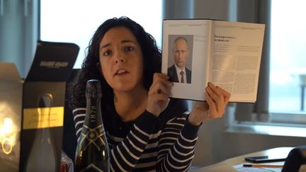 La député européenne Manon Aubry montre la "photo" et le "champagne" offert par Vladimir Poutine aux députés européens. (CAPTURE D'ÉCRAN YOUTUBE)