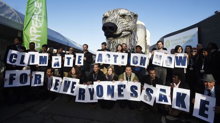 Des activistes de Greenpeace réclament "l'action immédiate, pour le bien de tous", devant l'ours géant Aurora, pendant une manifestation lors de la COP21, au Bourget, le 9 décembre 2015. (DOMINIQUE FAGET / AFP)