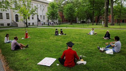 Des étudiants de Harvard assis sur une pelouse, le 28 mai 2020, à Cambridge (Massachusetts). (BRIAN SNYDER / REUTERS)