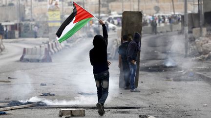 Un jeune Palestinien brandit son drapeau lors d'affrontements avec l'arm&eacute;e isra&eacute;lienne, le 6 octobre 2015, au check-point de Qalandia, pr&egrave;s de Ramallah (Cisjordanie).&nbsp; (MOHAMAD TOROKMAN / REUTERS)